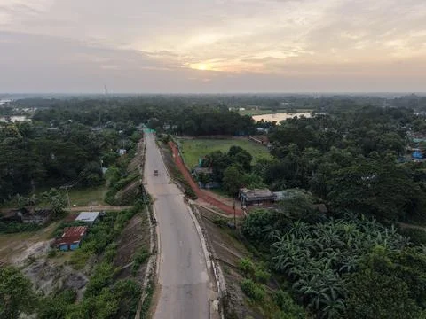 High aerial drone view of an elevated rural road at sunset through greenery Stock Photos
