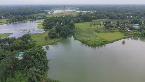 High aerial drone view of green farmland, lake, and brick kiln in countryside Stock Footage 341523587
