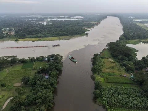 High aerial drone view of a river conjoining another river past green fields Stock Photos