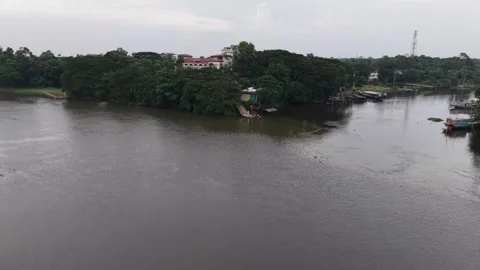 High aerial drone view of a wide river flowing past a green riverside town Stock Footage 341520370