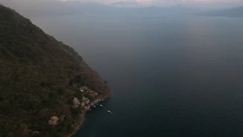 High aerial looking down shore of Lake Atitlan and steep hillsides in Guatemala Stock Footage 329013724