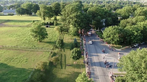 High aerial of parade, candy throwing, floats and vehicles along beautiful Stock Footage 116975958