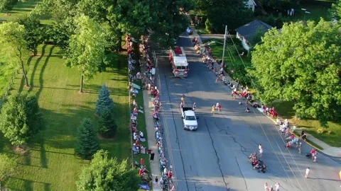 High aerial of parade, candy throwing, floats and vehicles along beautiful Stock Footage 155629929