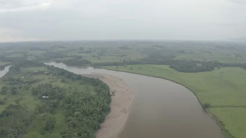 High aerial pulls back above the Orteguaza river to reveal a ferry sailing Stock Footage 104713008
