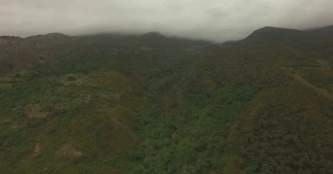 High Aerial shot between clouds and green mountains Stock Footage 76921054