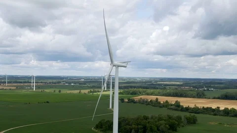 High aerial view row of wind turbines on green farm fields with cloudy sky Stock Footage 121020744
