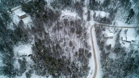 High Aerial View of Sharp Curve on Snowy Dirt Road and Winter Houses Stock Photos