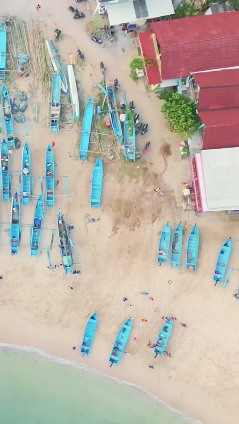High aerial view shows numerous blue fishing boats spread across a sandy tr.. Stock Footage 341543910