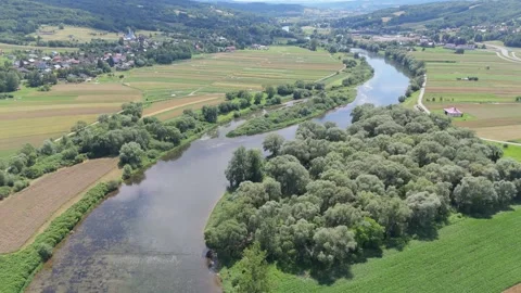 High aerial view of a winding river passing through patchwork farmland and green Stock Footage 324520394
