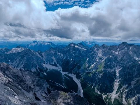 High Alpine Mountain Range with Deep Valleys and Clouds Stock Photos