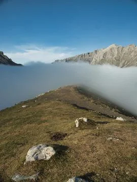 High alpine ridge over thick cloud inversion - Hiking trail on a grassy rid.. Stock Photos