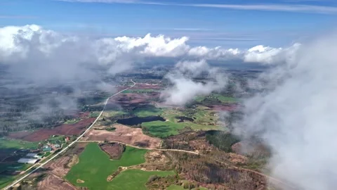 High-altitude aerial pan through clouds reveals vast Latvian countryside Stockbeeldmateriaal 334123764