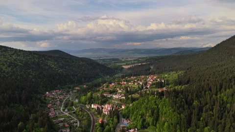 High-altitude aerial view of a mountain valley town between forested ridges Stock Footage 336316169