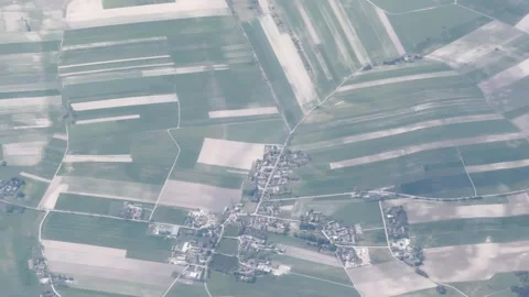 High altitude aerial view of patchwork farmland and a small village, with pale 動画素材 337736602