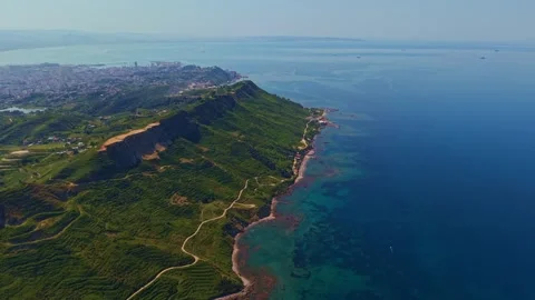 High altitude drone flight over green cape and coastline near coastal city Stock Footage 337792089