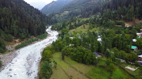 High-altitude drone shot of crystal-clear Himalayan river cutting through green Stock Footage 310656157