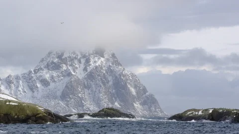 High altitude mountains with foggy sky background and ocean waves splashing Stock Footage 121574432