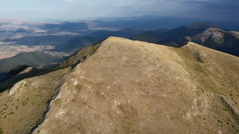 High altitude rocky peak overlooking farmland and distant layered ranges Stock Footage 344095454