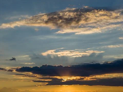 High-altitude view of layered clouds illuminated by hidden sunrays, creating  Stock Photos