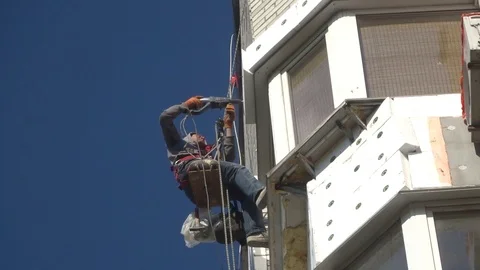 High-altitude worker with a drill insulates the balcony Stock Footage 93302635