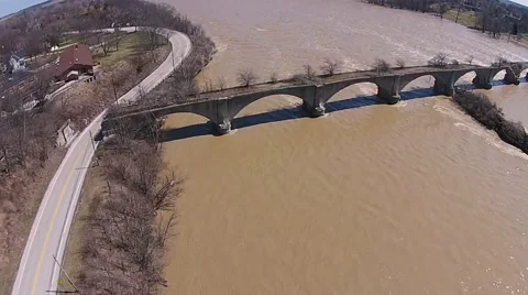 High and Fast Moving River flowing past deteriorating abandoned bridge aerial. Stock Footage 40340547