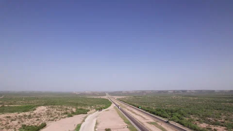 High angle of 18 wheelers driving on I-10 in the West Texas desert Stock Footage 308959565
