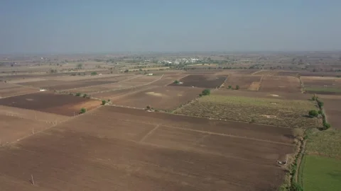 High-angle aerial drone clip over vast brown tilled soil fields during a clear Stock Footage 337172291