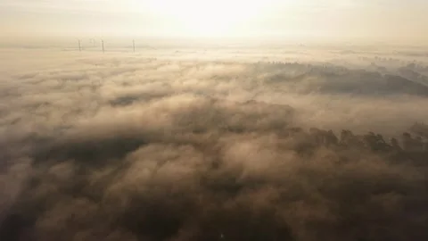 High-angle aerial drone view of a thick morning fog enveloping a rural land Stock Footage 338130006