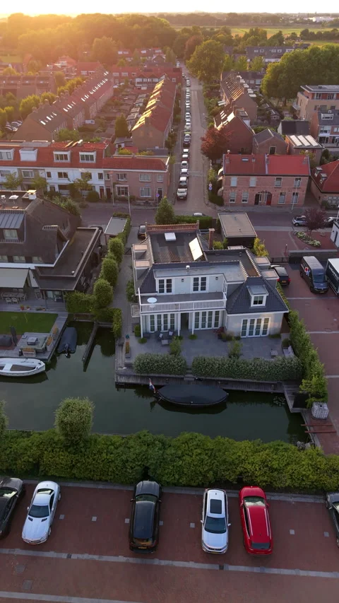 High-angle aerial drone view of luxury waterfront villa along canal, parked Видео 347160313