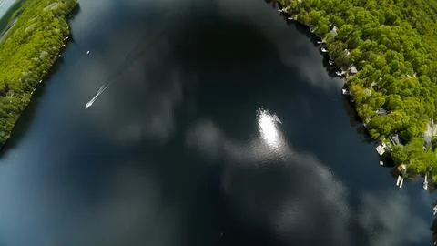 High angle aerial perspective looking down at a boat on a sunlit lake surface Stock-Fotos