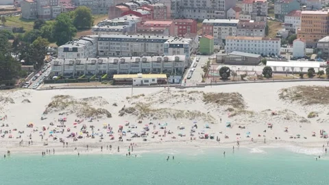 A high-angle aerial shot captures a lively beach scene in Laxe, Spain. The sandy Stock Footage 346710637