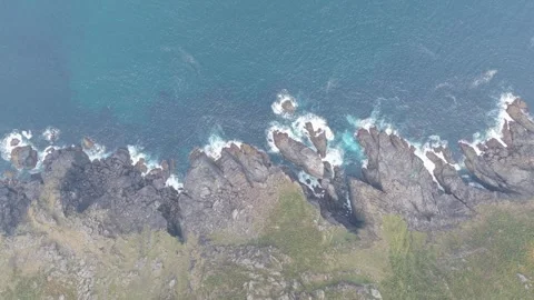 A high-angle aerial shot captures the dramatic rocky cliffs and rugged coastline Stock Footage 346714635
