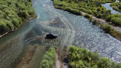 High angle aerial view of 4x4 off-road vehicle navigating through river Video stock 334624943
