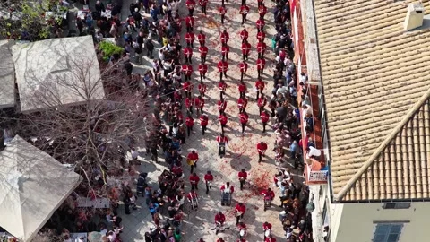 High angle aerial view of a marching band in red uniforms parading through the Stock Footage 333783931