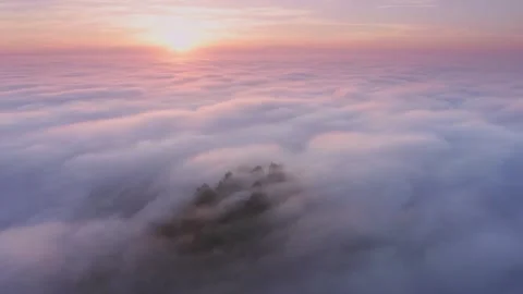 High angle aerial view of a misty mountain peak above a sea of clouds at sunrise 動画素材 345721543