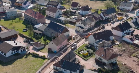 High angle aerial view of road construction and trucks in small village Stockbeeldmateriaal 329565637