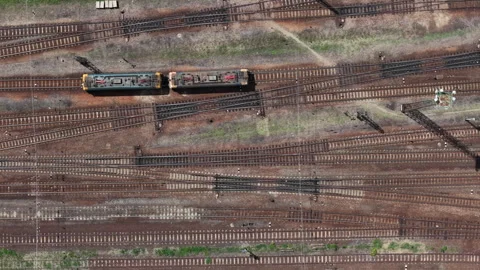 A high-angle aerial view shows two electric train engines sitting on a complex Stock Footage 337472328