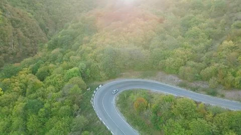 High angle aerial view of single silver car driving on sharp hairpin curve .. Stock Photos
