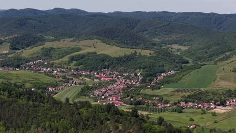 A high-angle aerial view of a small Hungarian village surrounded by lush green Stock Footage 336707476