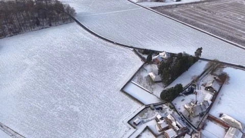 A high angle aerial view of a snow blanketed rural landscape. A small cluster Video stock 329429179