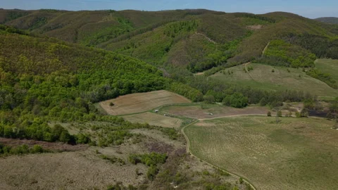High angle aerial view of vibrant rolling hills and dense forests surrounding 動画素材 334237353