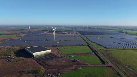 High angle aerial view of wind turbine blades turning over massive fields of Stock Footage 336950576