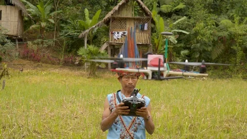 High angle camera rotation shot of an old indigenous man controlling a drone Stock Footage 113178707