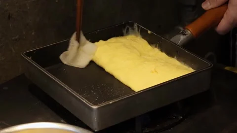 High-Angle Close-Up of Chef Rolling Japanese Tamagoyaki Omelet in Square Iron Pa Stock Footage 333527348