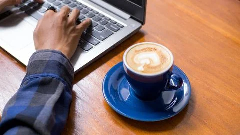 High Angle Close Up of Coffee Cup and Hands Typing on Laptop Stock Photos