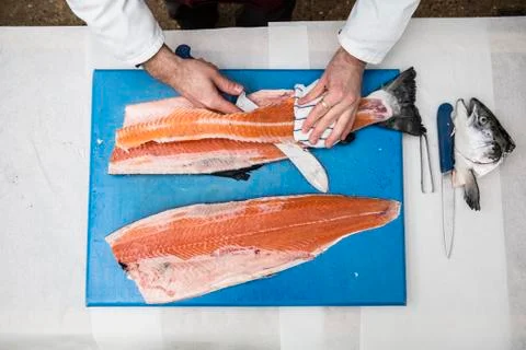 High angle close up of fishmonger standing at a table, cutting and filleting Stockfoto's