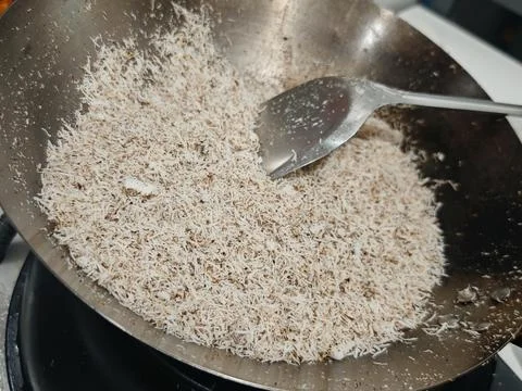 High Angle Close Up of Grated Coconut Being Toasted in a Metal Wok Stock Photos