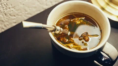 High-angle close up of mate tea brewing in a mug with a bombilla straw Stock Footage 346072295