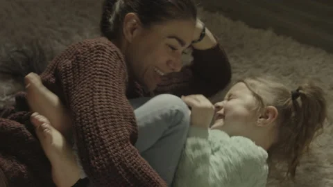 High angle close up of mother laying on floor tickling daughter / South Jordan, Vidéo 154104050