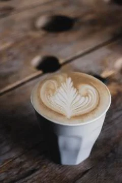 High angle close up of mug with cafe latte topped with intricate foam pattern on Fotos de archivo